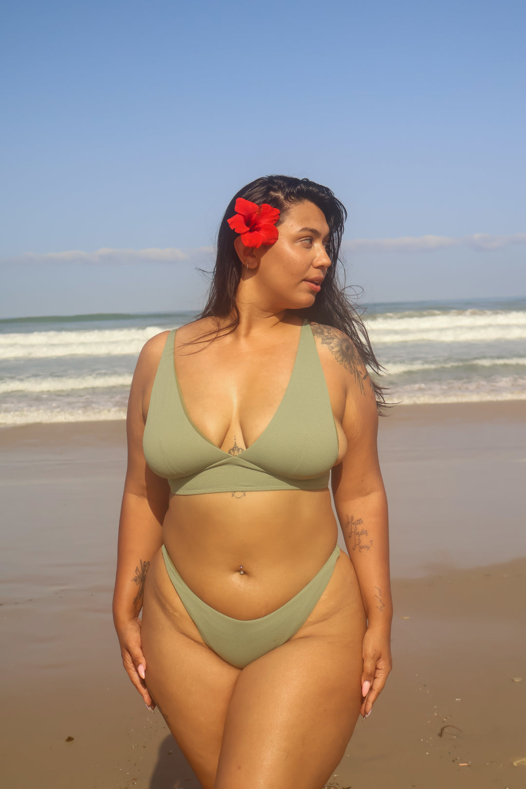 דוגמנית על חוף הים עם ביקיני ירוק של Lika Swimwear, טופ עם מחשוף בצורת V ותחתון תואם